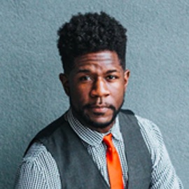 A man smiling with an orange tie